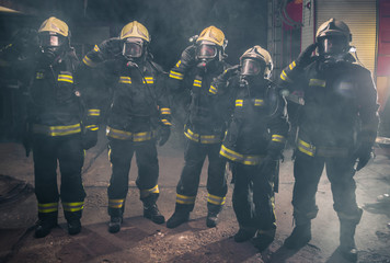Team of fireman standing the middle of the fire extinguisher's smoke inside the fire department
