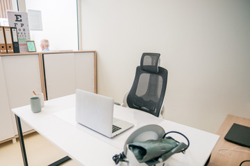 Bright and Modern Medical Doctor's Office with laptop, lamp and modern chair.