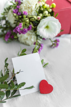 Postcard with a flowers, heart and an empty tag for text. Romantic greeting and surprise. Concept of love, Happy mother's Day and Valentine's Day on white background. Selective focus. copy space