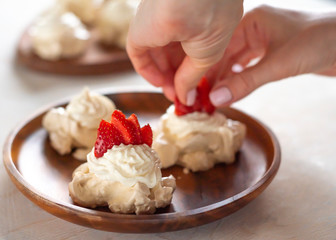 the process of creating Pavlova dessert, decorating the meringue with strawberries