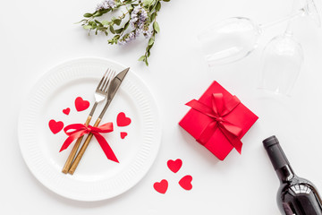 Romantic dinner on Valentines Day. Wine, plate, present box on white background top-down