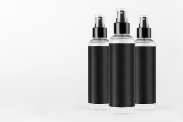 Three tall transparent spray dispenser bottles for cosmetics with black label on white background, mock up for branding,  presentation, design.