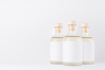 Group glass bottles for cosmetic, perfume, alcohol drink with  white label, cork, yellow liquid on white background, mock up for  design.