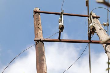 Electricity pole, fuses and cable against the sky