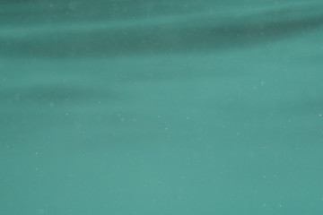 Abstract underwater under the surface of a turquoise sea in selective focus.