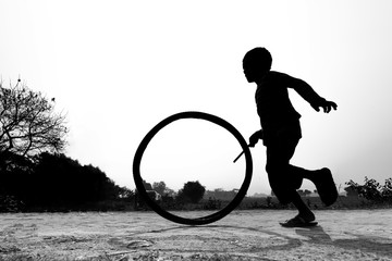 Bangladesh – January 24, 2020: A restless boy is playing on the village road with old discarded tires at Savar, Dhaka, Bangladesh.