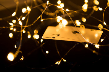 Two black aces cards in blur Christmas lights.