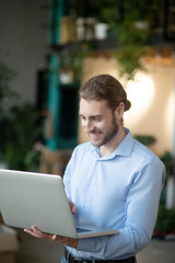 Young man in light blue shirt with laptop in his hands.