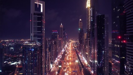 Aerial night illuminated Dubai city skyline skyscrapers view and  busy traffic on Sheikh Zayed road  highway - Powered by Adobe