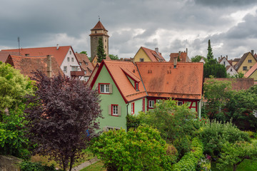 Fototapeta na wymiar Beautiful old green house among green trees, roofs medieval city of Rothenburg ob der Tauber in the background, Bavaria, Germany.