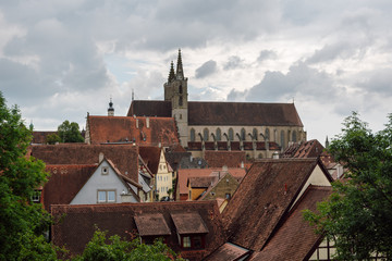 View of the church of St. James and roofs of houses in the city of Rothenburg ob der Tauber in Bavaria, Germany, at rany day. - obrazy, fototapety, plakaty