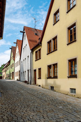 Fototapeta na wymiar A typical narrow paved street with colorful traditional houses for the medieval town of Rothenburg ob der Tauber located on the famous Romantic Road in Bavaria,Germany.