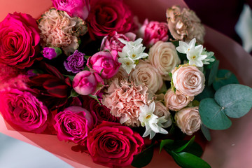 Close-up flowers in hand. Florist workplace. Woman arranging a bouquet with roses, chrysanthemum, carnation and other flowers. A teacher of floristry in master classes or courses