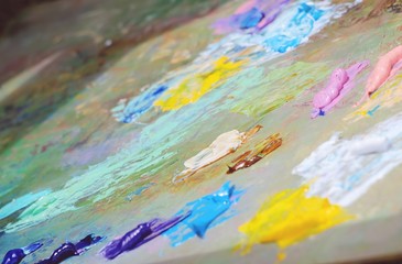 Obraz premium Close up mixing oil paints on the palette. Colorful workplace of the artist with oil paints. Oil paints texture background.