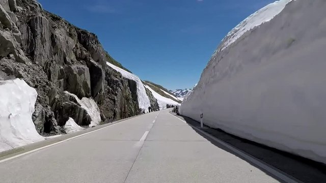 Motorcycle curves driving on mountain roads by motorbike to the Nufenen Pass along walls of snow. Includes four different video sequences!