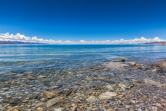 Stunning Panorama View Namtso Lake (Lake Nam, Tengri Nor) Western Nyenchen Tanglha Mountains On Qing Zang Plateau, Summer Sunny Day With Blue Sky Could Background, Clear Water And Stone, Tibet, China.