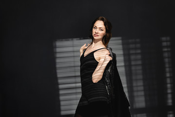 beautiful young girl, self-confident, stands in the sun. Women's coat on the shoulders. Makeup for every day.