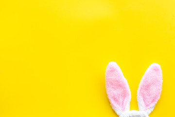 Easter bunny concept. Toy rabbit's ears on yellow background top-down copy space