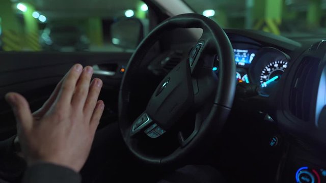 Man driving in innovative automated car using self-parking autopilot for parking on parking lot
