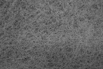 Cleaning sponge rubbing surface close up with blue effect in black and white.