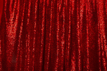 red drapery made of bright shiny fabric with round pleats hanging in folds