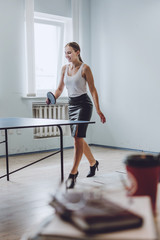 Fototapeta na wymiar Lunch break activities concept. Office games during Lunch break. Attractive young Business woman playing ping pong, table tennis in office