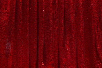 red drapery made of bright shiny fabric with round pleats hanging in folds