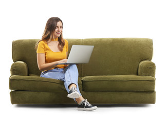 Young woman with laptop sitting on sofa against white background