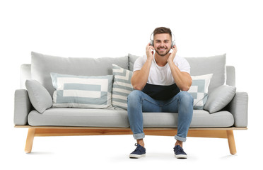 Young man listening to music while sitting on sofa against white background