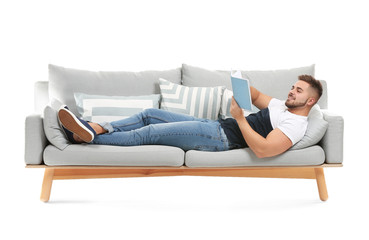 Young man with book lying on sofa against white background