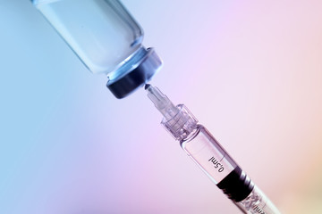 Syringe with filler for cosmetology and ampule on light background, closeup