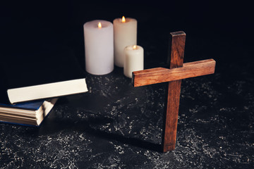 Christian cross, Bible and candles on dark background