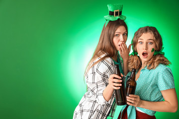 Surprised women with beer on color background. St. Patrick's Day celebration
