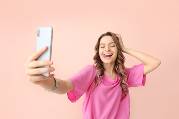 Naklejka premium Young woman taking selfie on color background