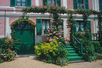 The house and home of Claude Monet at Gverny with rose coverd arches and plants and flowers