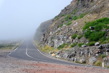 Mountain road disappearing into fog on Madeira island