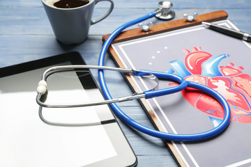 Stethoscope with tablet computer and drawing of human heart on table