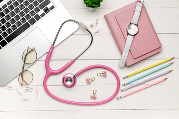 Stethoscope with laptop and stationery on wooden table