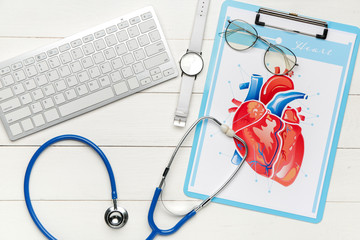 Stethoscope with computer keyboard and drawing of human heart on wooden table