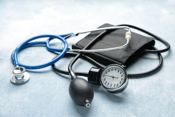 Stethoscope with sphygmomanometer on color background