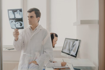 In medical room two young doctors radiologists analyzing x-ray