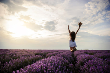 back view of a woman in white dress and a hat jumping in the lavender field