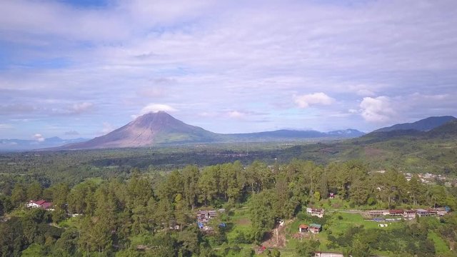 Aerial footage flying over a beautiful green village towards mount Sinabung volcano. Berastagi, Indonesia