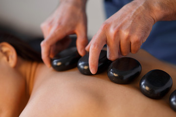 Young Asian woman enjoying the therapeutic effects of a traditional hot stone massage at luxury spa and wellness center