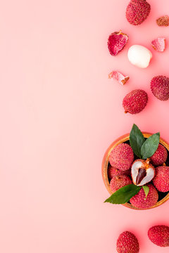 Fresh ripe lychee in bowl on pink desk top-down frame copy space