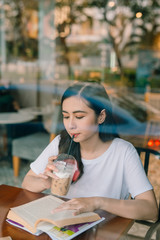 Picture of young pretty woman sitting at the table in cafe and reading book.