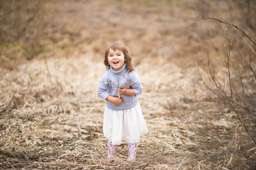 Naklejka na ściany i meble little cute girl in spring looks at willow tree branches and buds
