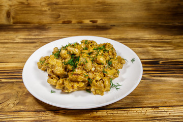 Stewed mushrooms with sour cream on wooden table