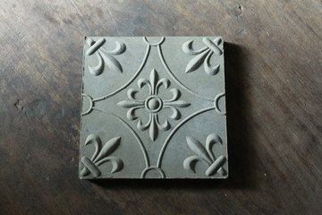Top view of floor tiles embossed with floral motifs. Gray blend with the color of the rocks suitable for outdoor