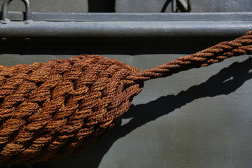 Old weathered ship woven rope fender hanging on side of old military ship